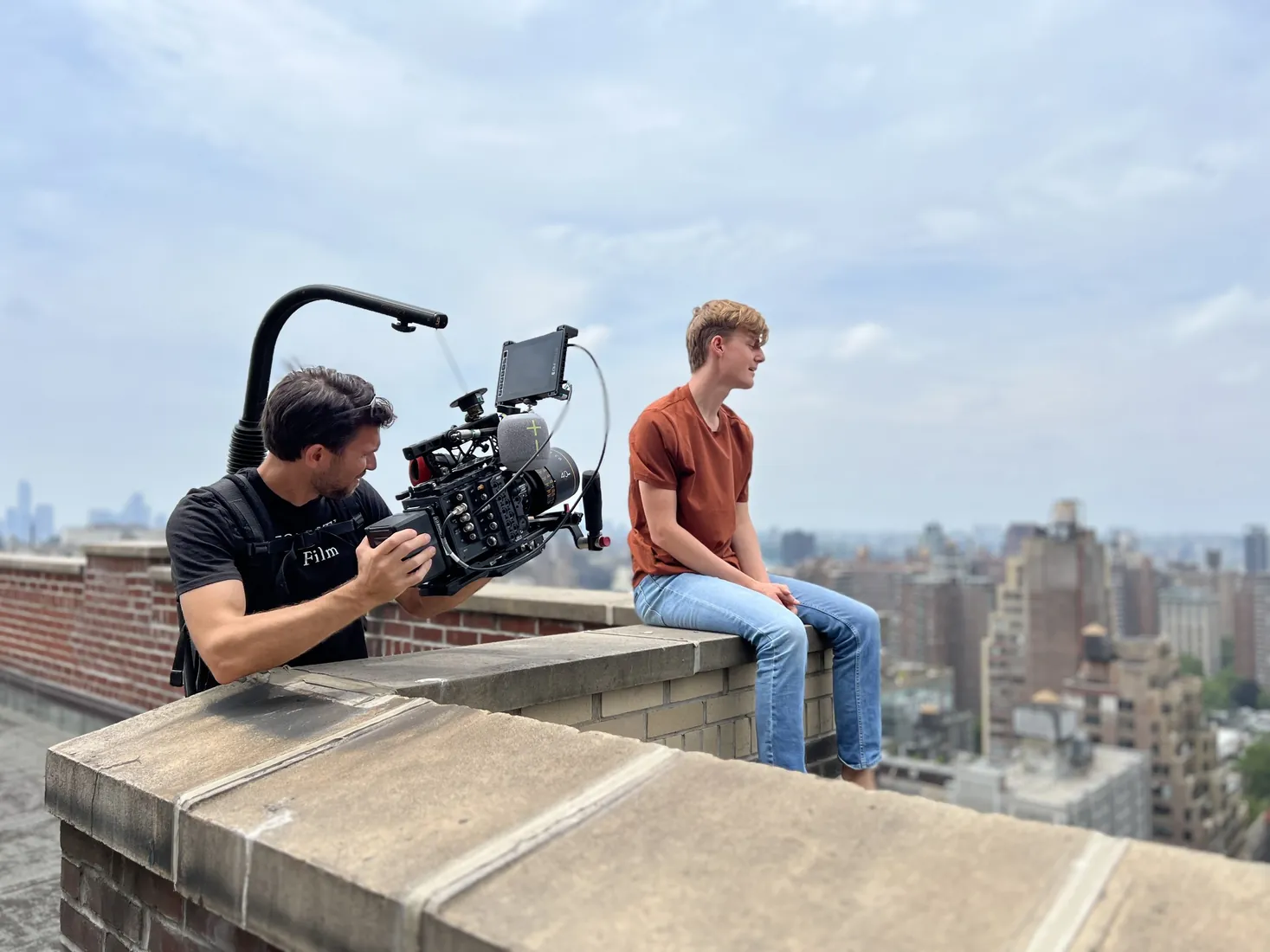A camera operator filming an artist on a Manhattan rooftop.